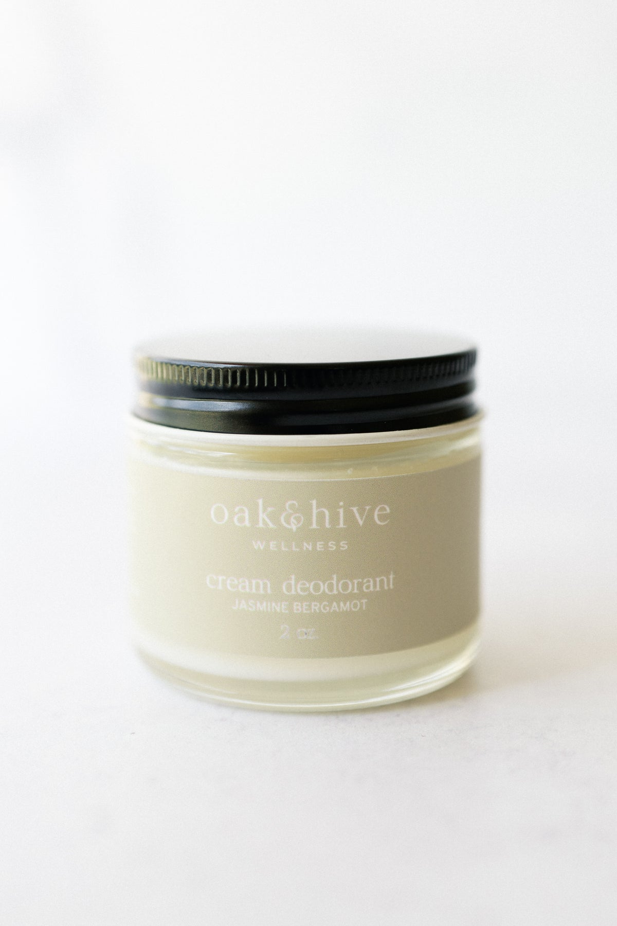 a jar of jasmine bergamot deodorant with a yellow label, a black lid on a white background.