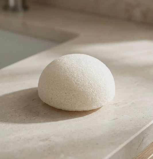 Round white object which is the facial sponge on a light surface with soft shadows