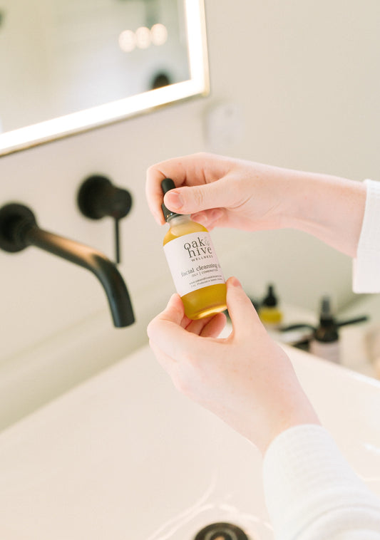 Person holding a bottle of 'Oak + Hive' product in a bathroom setting