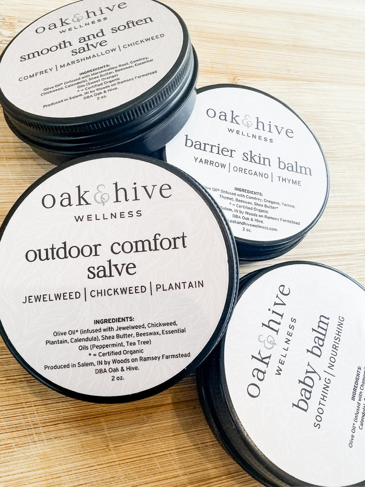 Tins of Oak & Hive Wellness salves and balms on a wooden surface