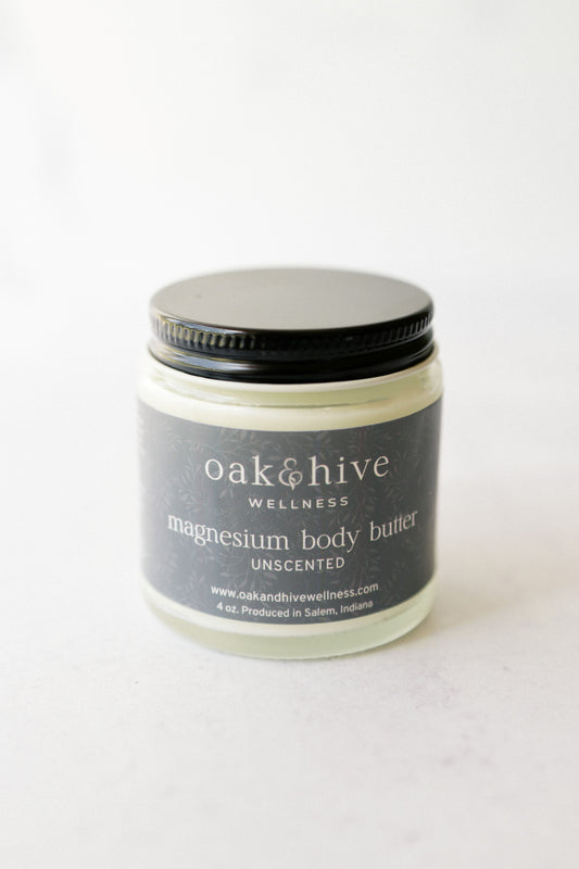 a jar of 'Oak & Hive Wellness Unscented Magnesium Body Butter' with a green label and a black lid on a white surface.