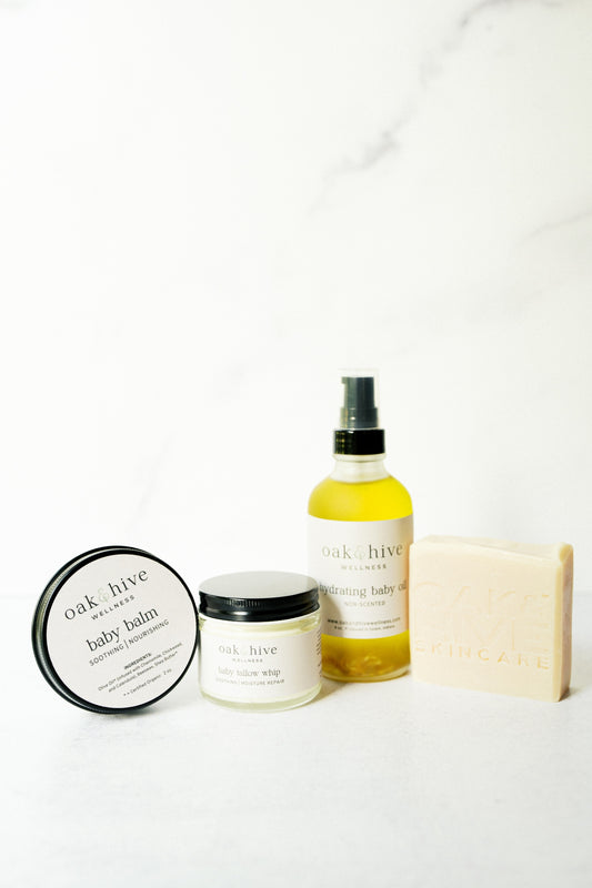 Collection of Oak & Olive products including a bottle of oil, jar, a black tin, and soap on a white background