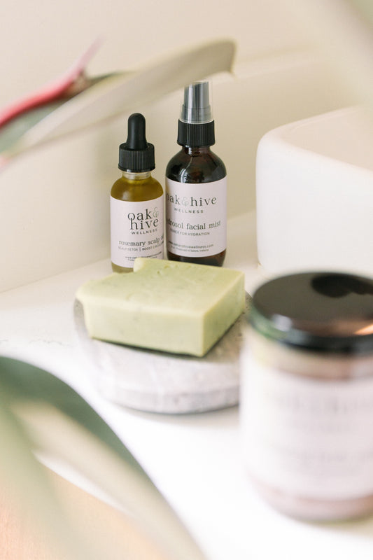 Three bottles of 'Oak + Hive' skincare products on a marble surface.