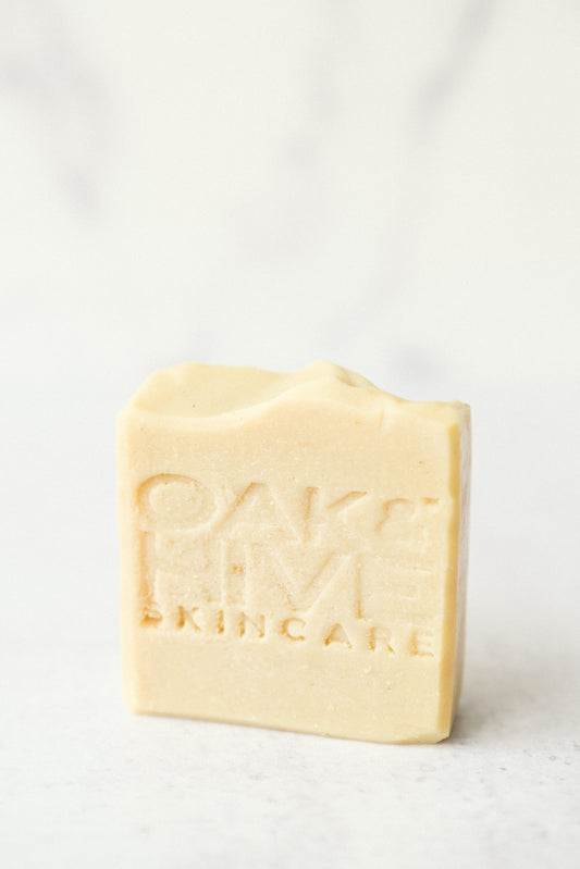A bar of soap with 'OAK & HIVE skincare' embossed on its surface, placed on a marble background.