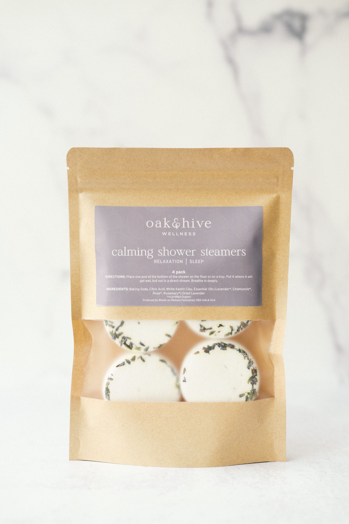 a brown package with white circles inside that has lavender flowers on the pucks, and a purple label on a white background. 