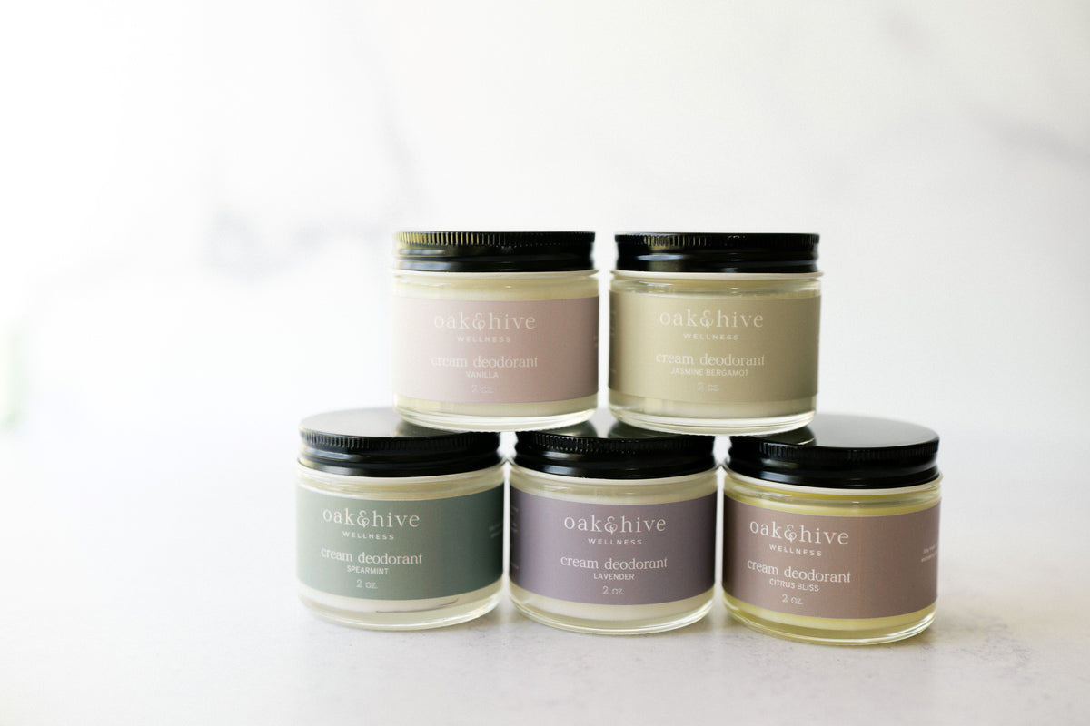 Five jars of cream body deodorant in various colors, labeled with their respective scent names such as Citrus Bliss, Jasmine Bergamot, Lavender, Spearmint, and Vanilla.