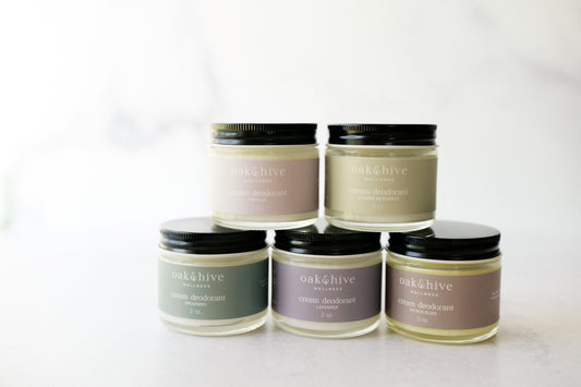 Five jars of cream body deodorant in various colors, labeled with their respective scent names such as Citrus Bliss, Jasmine Bergamot, Lavender, Spearmint, and Vanilla.