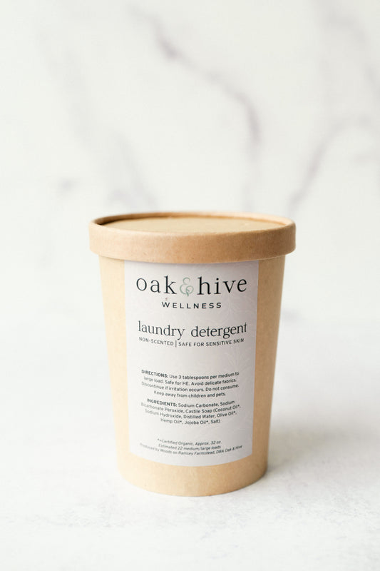 A beige container labeled 'oak & hive wellness laundry detergent' with product details on the label.