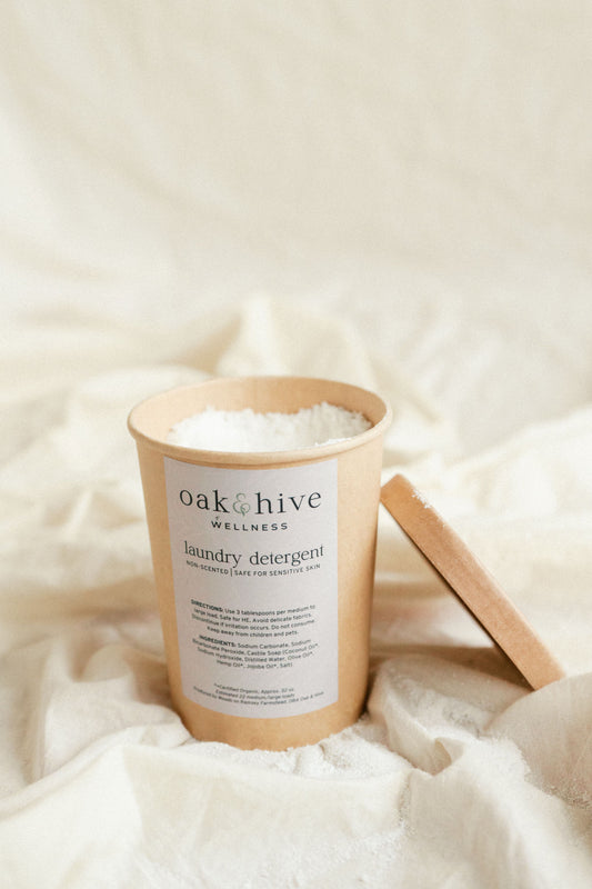 a brown container with the lid off and sitting next to it, with white powder inside of the container sitting on a wrinkled cream fabric. 