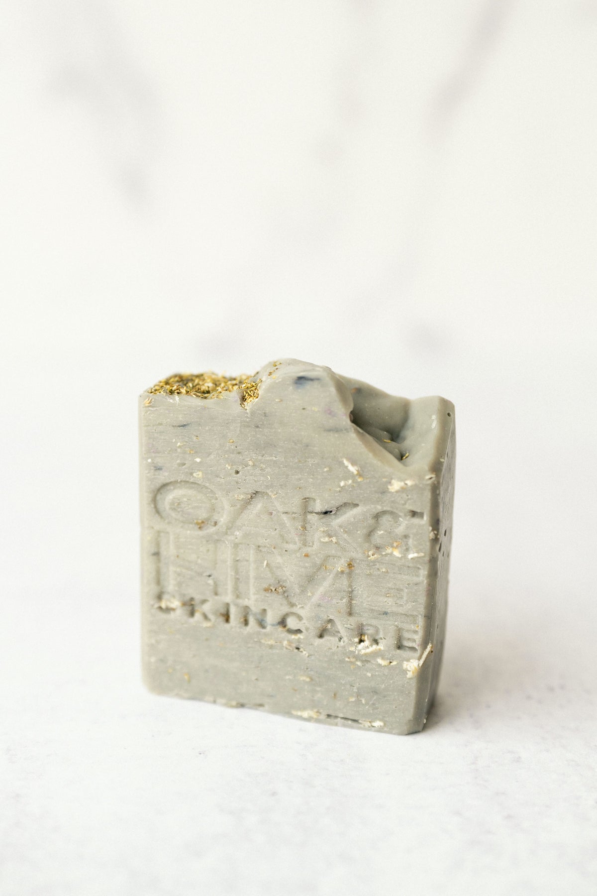 a purple gray bar of soap with white flakes in it on a white background. 