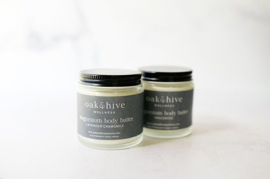 Two jars of magnesium body butter with black lids and labels that read 'oak & hive', one with lavender and chamomile scents, the other with unscented label.