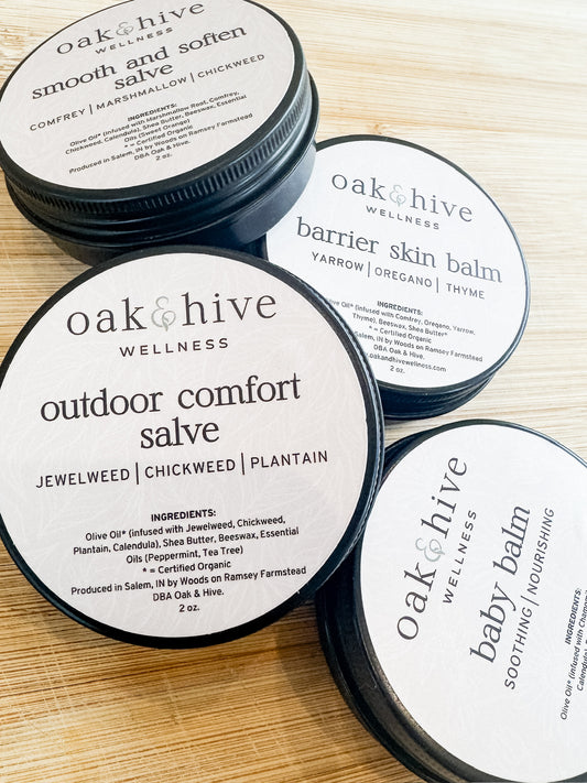 Tins of Oak & Hive Wellness salves and balms on a wooden surface