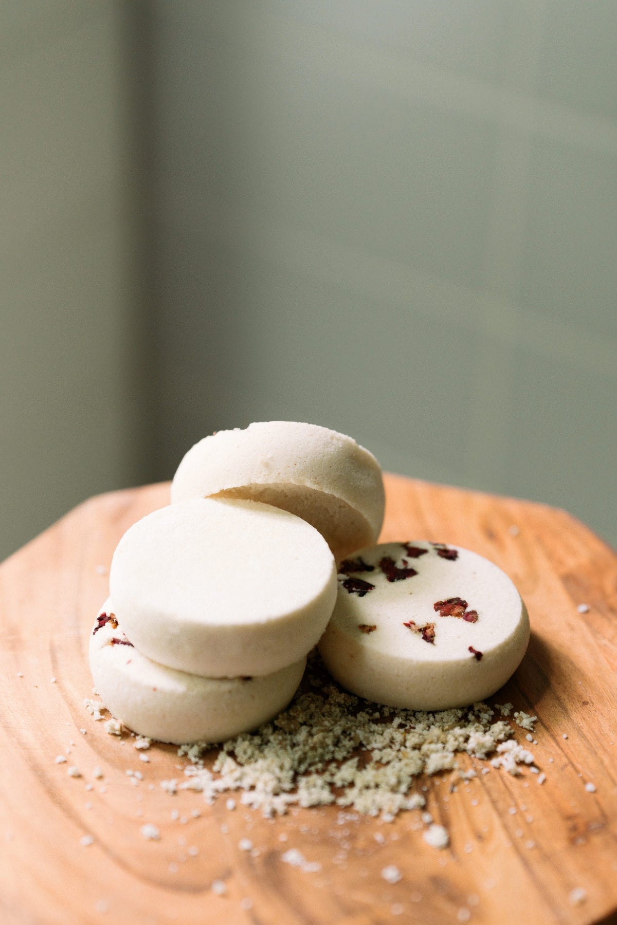 Three shower steamers with red specks on a wooden surface with a blurred green background