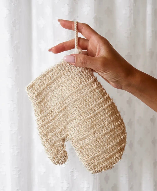 Hand holding a beige knitted sisal exfoliating mitt against a white background.