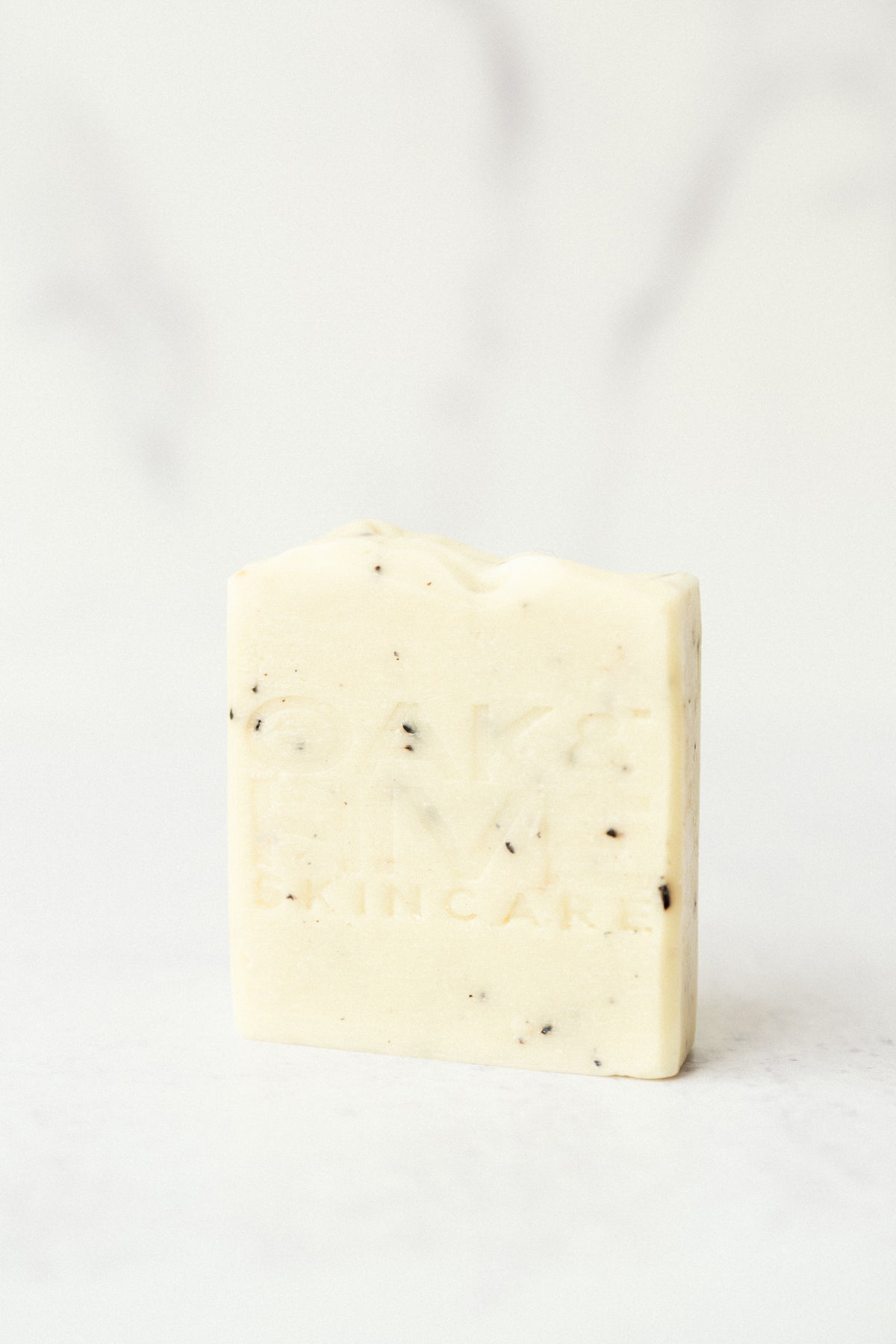 a cream color bar of soap with dark brown specks on a white background