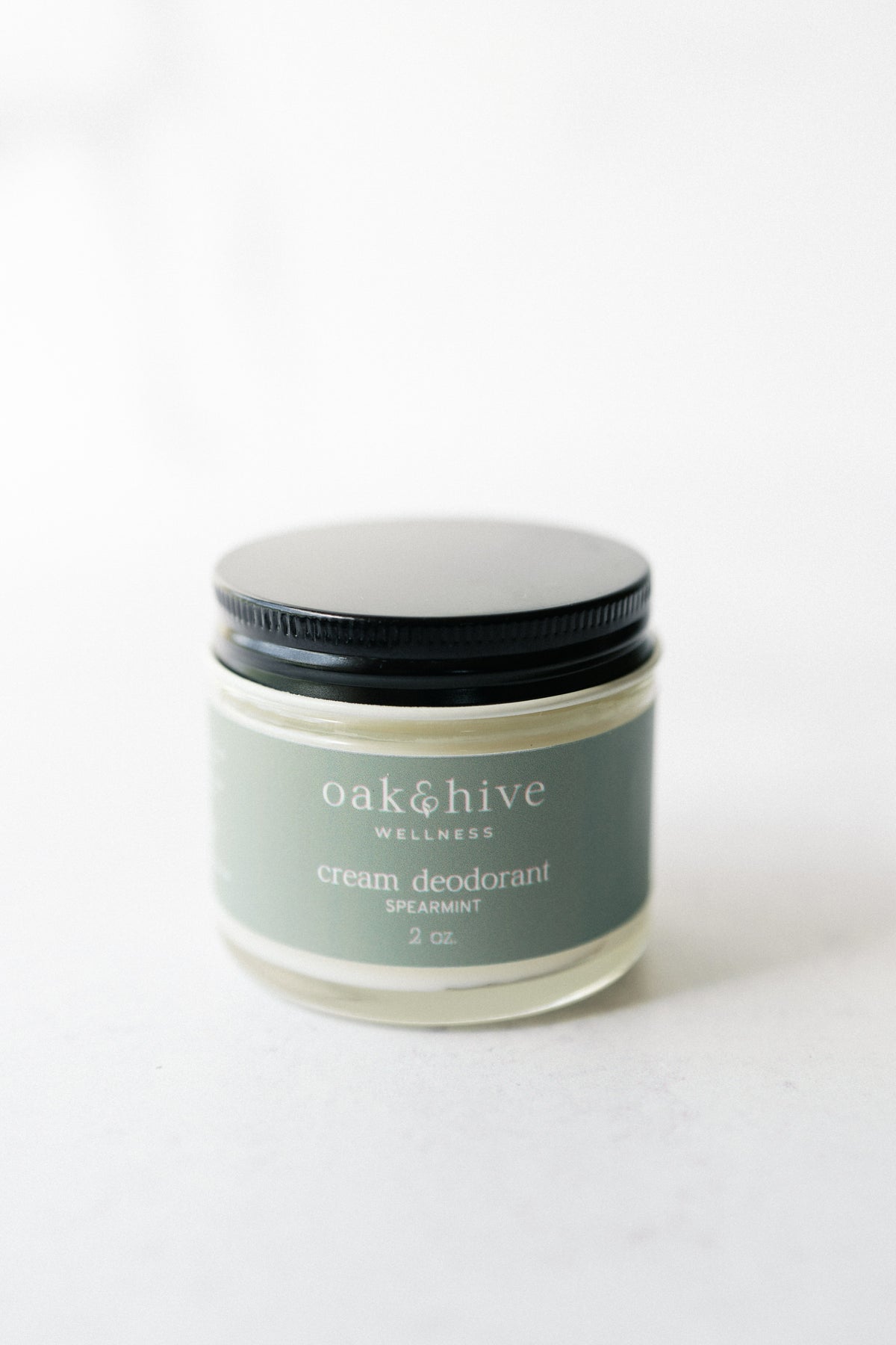 a jar of spearmint deodorant with a green label, a black lid on a white background. 