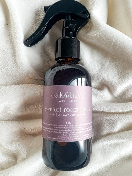 Black spray bottle with a pink label on a beige fabric background