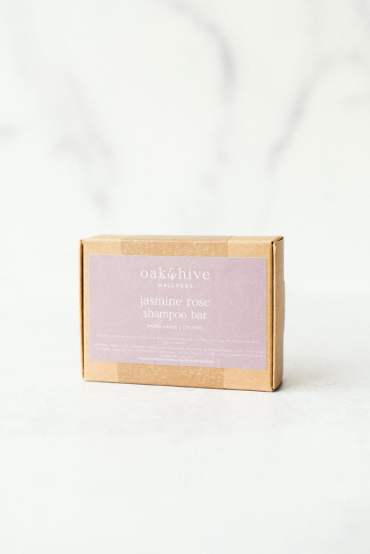 a brown box with a gray label that reads 'oak and hive wellness jasmine rose shampoo bar' on a white background. 